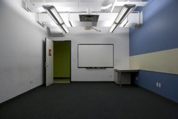 A small carpeted room with a whiteboard and a table along the far wall.